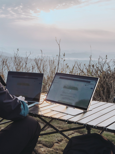 Man after a hike working on documents with Radiant monitor mirrored to his laptop outdoors